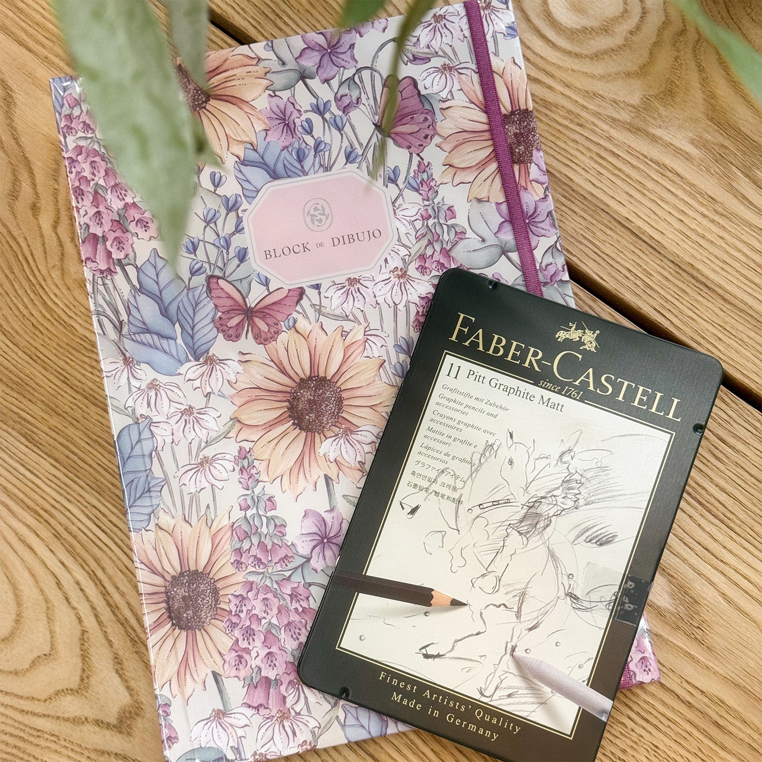 Block de dibujo y una caja de lápices de grafito.