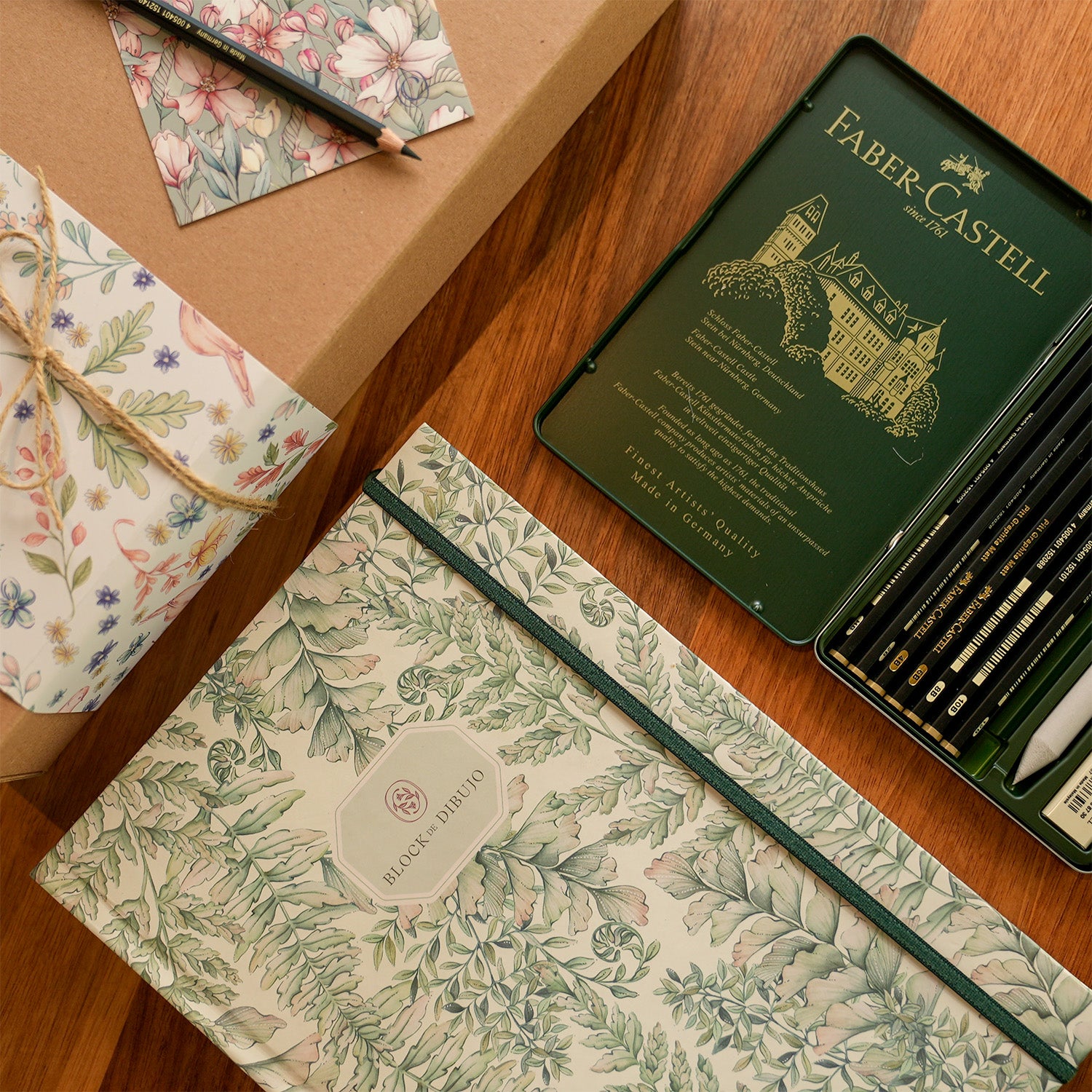 Block de dibujo y una caja de lápices de grafito.