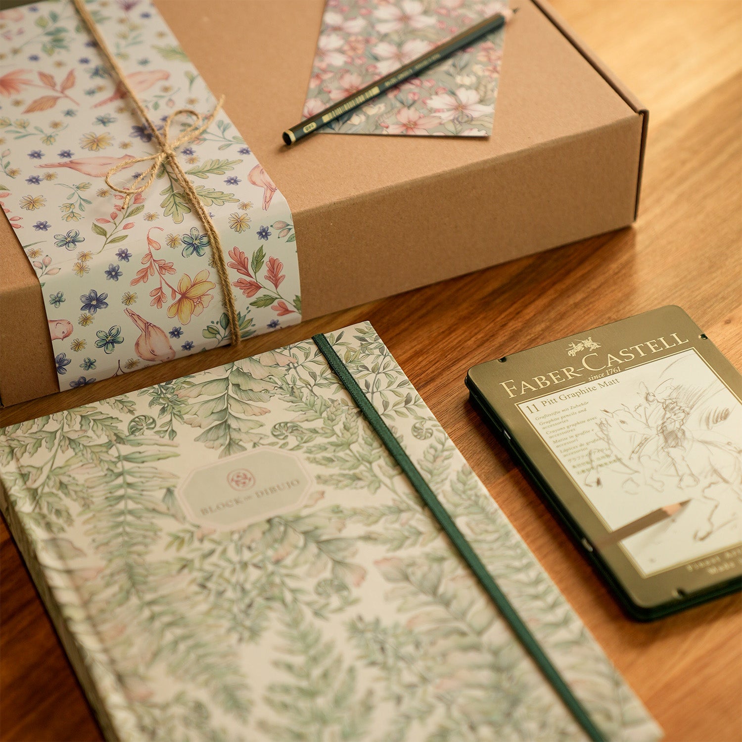 Block de dibujo y una caja de lápices de grafito.