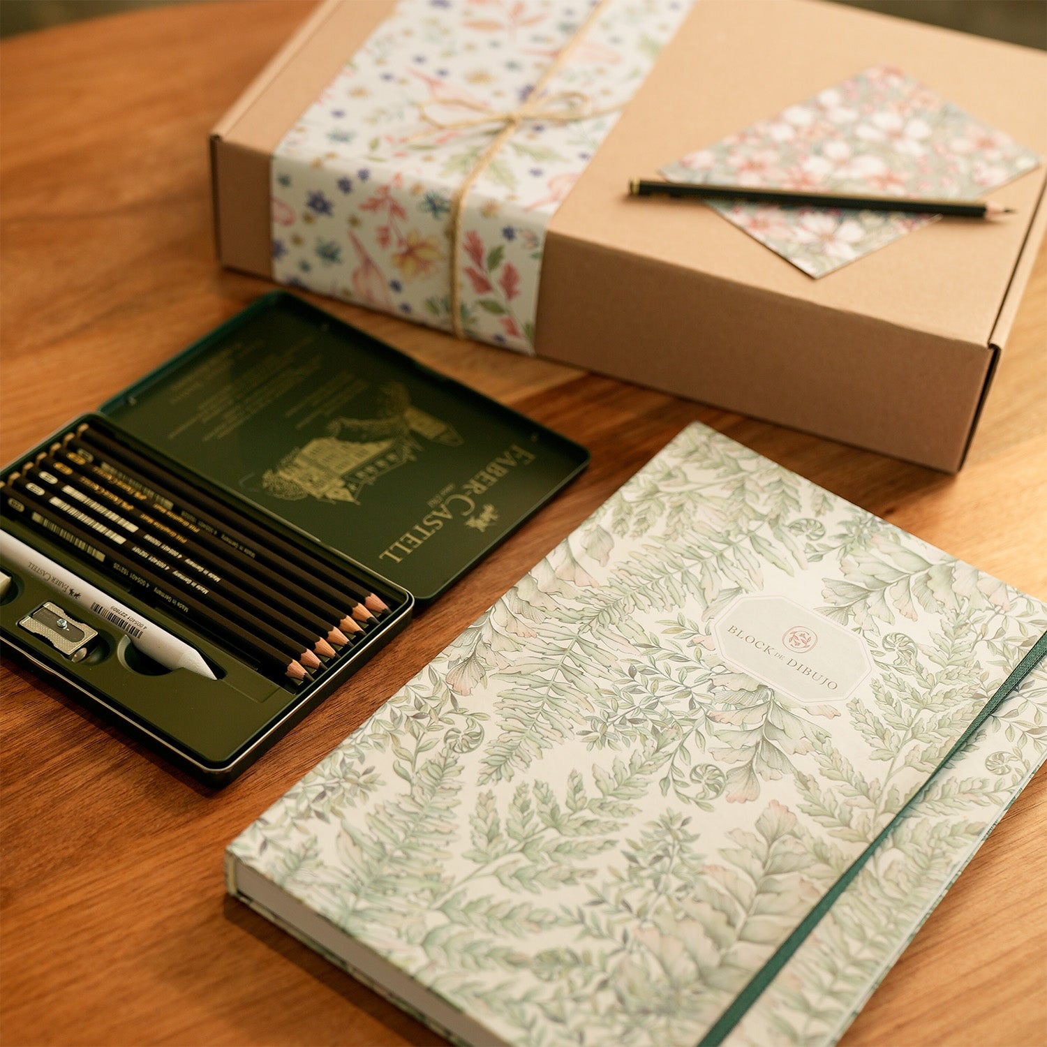 Block de dibujo y una caja de lápices de grafito.